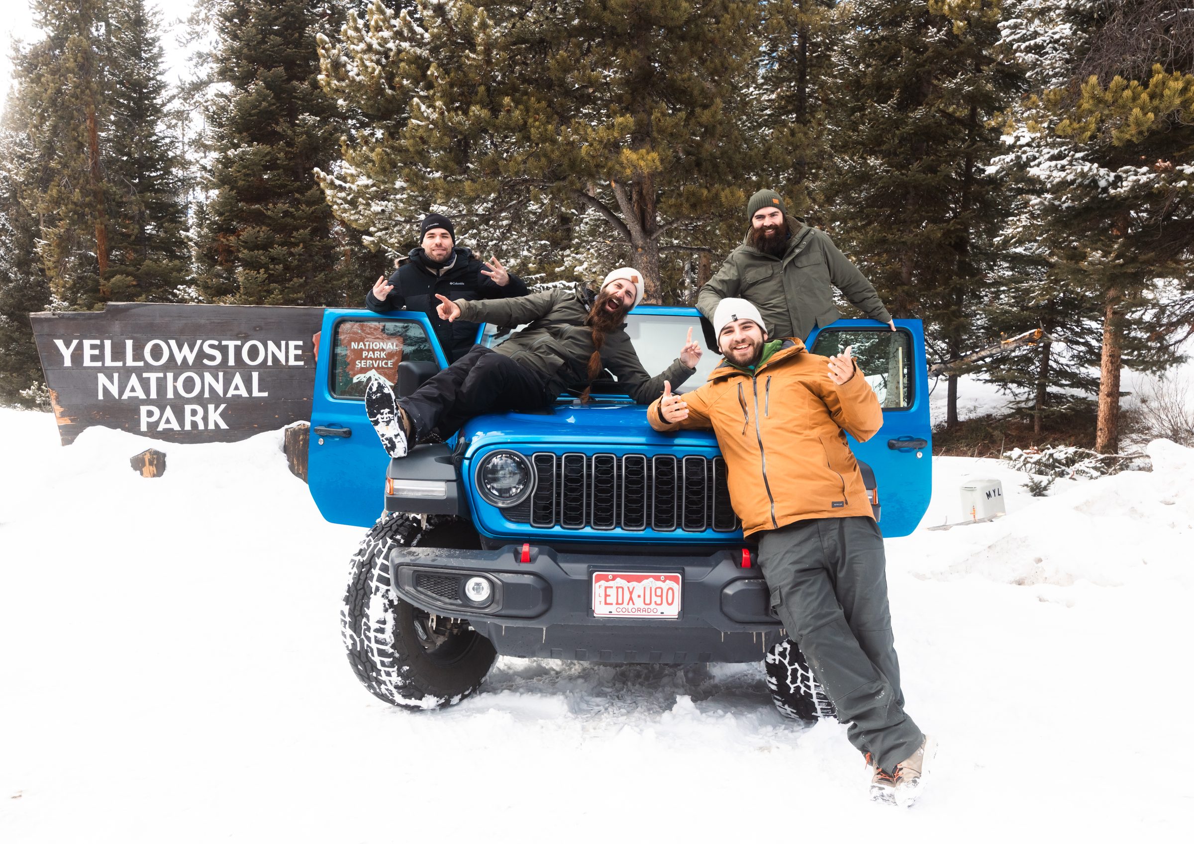 Greg y tres amigos con un todoterreno azul junto al cartel de Yellowstone National Park