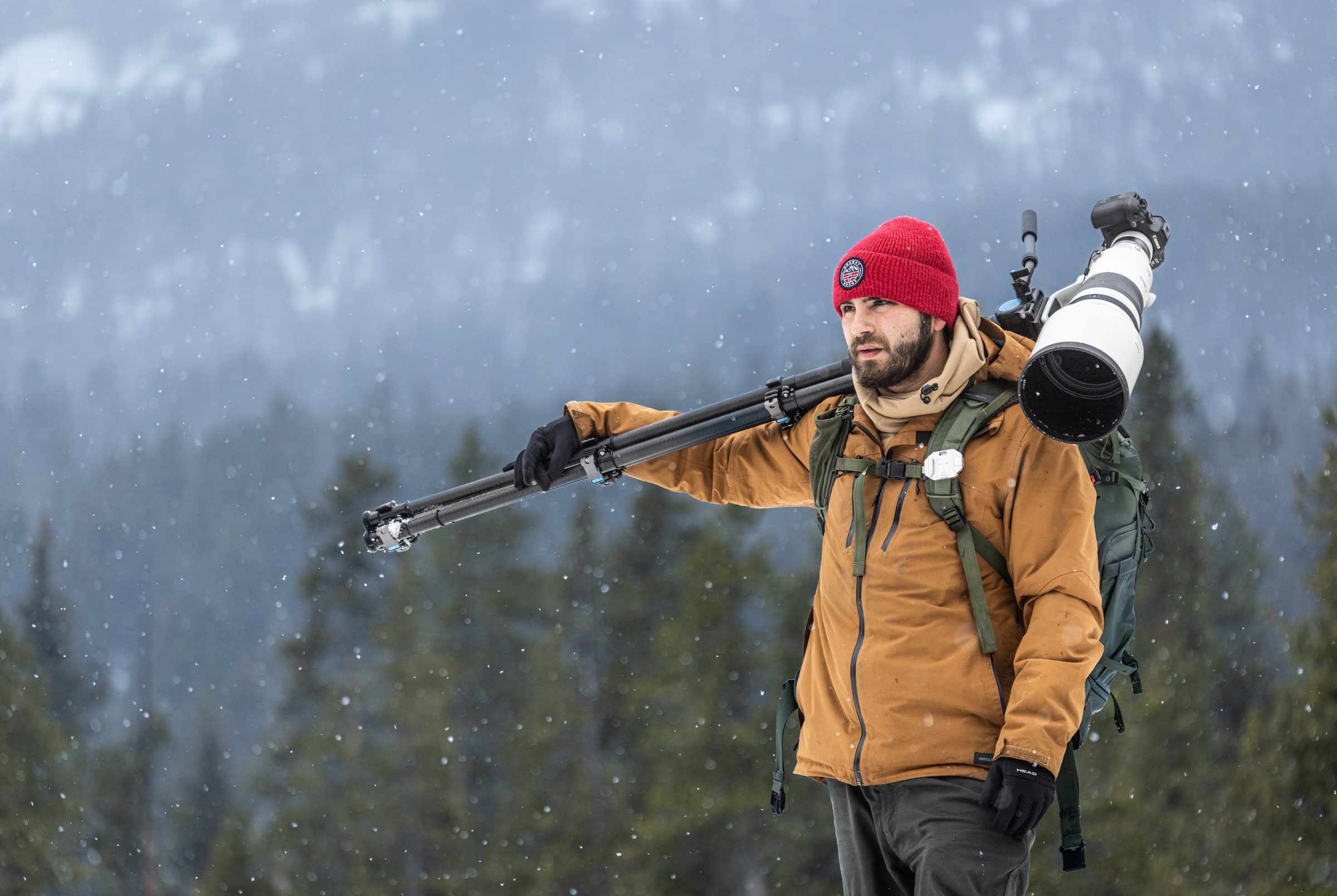 Greg cargando el trípode y el teleobjetivo en la nieve
