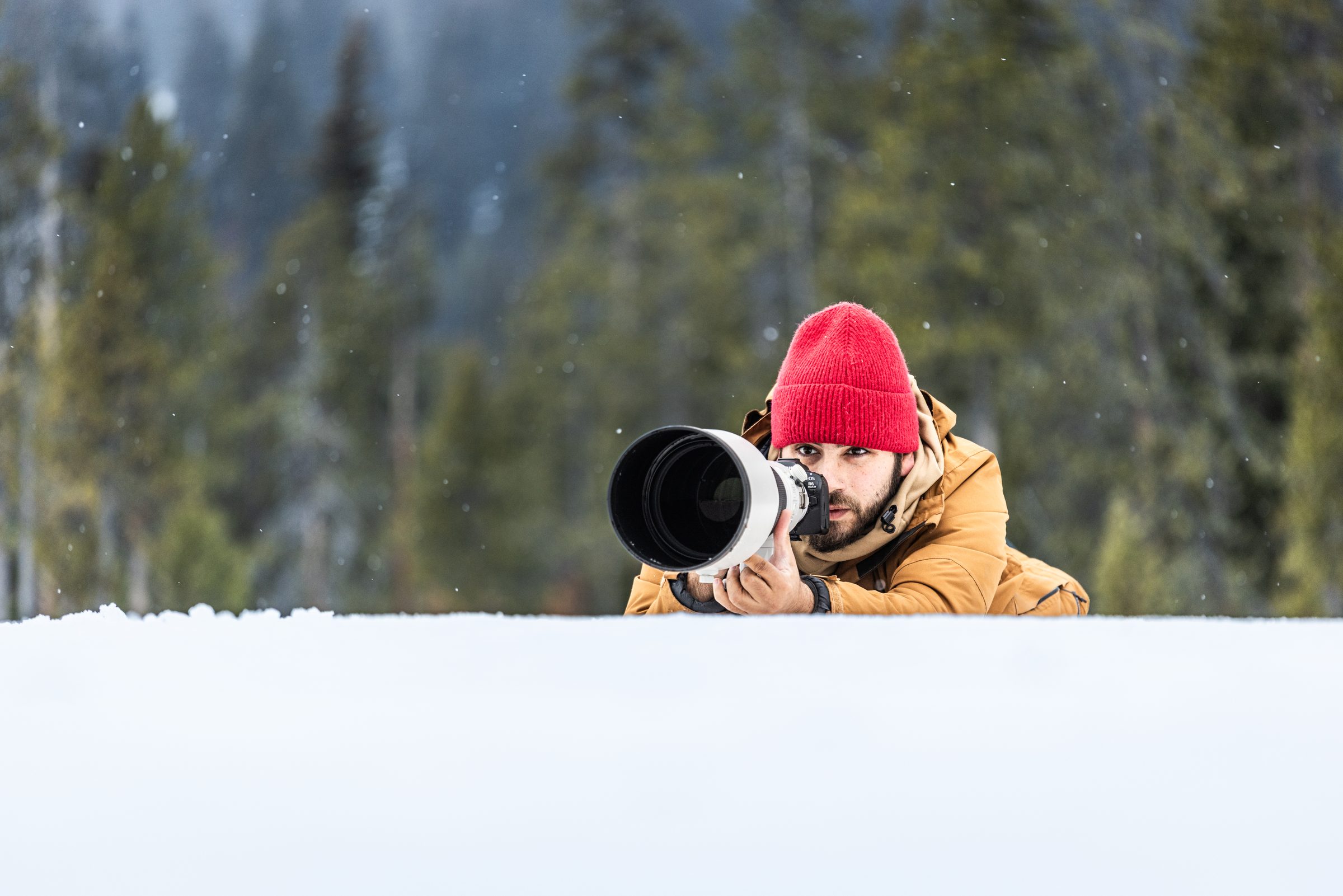 Greg tumbado en la nieve fotografiando con teleobjetivo